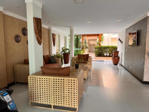 a lobby with wicker chairs and couches in a building at Orquídeas Praia Hotel in Porto Seguro
