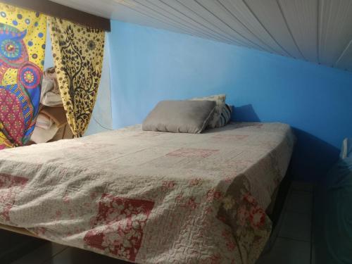 Cama pequeña en habitación con pared azul en Hostel & Cia Itanhaém, en Itanhaém