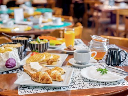 einen Tisch mit Teller mit Speisen und Tassen Kaffee in der Unterkunft Mercure Sao Paulo Moema in São Paulo