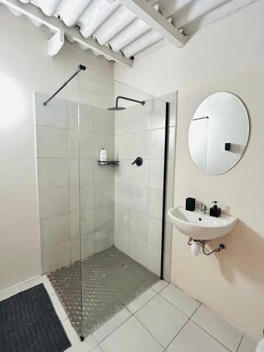 a bathroom with a shower and a sink and a mirror at Enez Place in Gqeberha