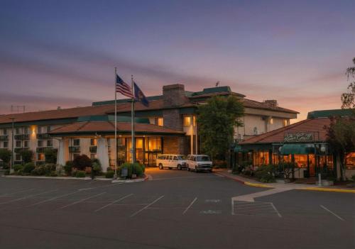 a hotel with two cars parked in a parking lot at Rogue Regency Inn Medford Airport in Medford