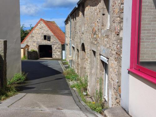 een stenen gebouw met een rood raam en een straat bij Paisible in Les Pieux