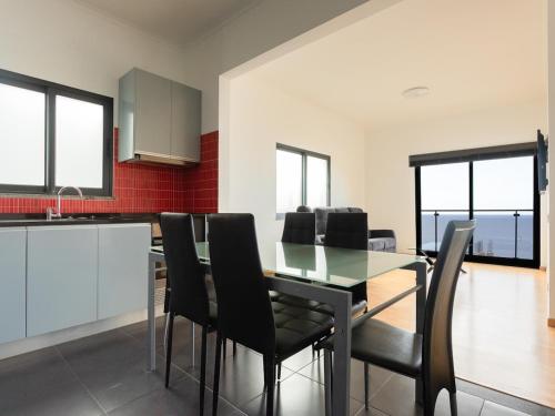 una sala da pranzo con tavolo in vetro e sedie nere di Skyline Villas RC a Calheta