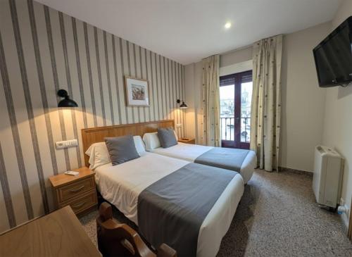 una habitación de hotel con una cama y un televisor en Hospedería Puerta de la Catedral, en Ciudad Rodrigo