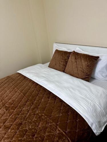 a bed with brown and white sheets and pillows at Udroiu Residence 2 in Craiova