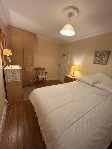 una camera da letto con un grande letto bianco e una sedia di 21 Balrath Wood - entire 3 bedroom house with drive and garden sleeps 5 a Kells