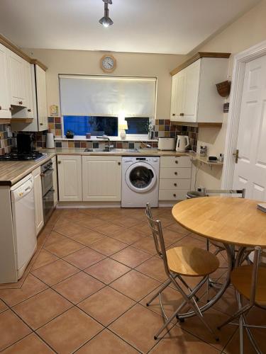 a kitchen with a table and a washing machine at Balrath Wood - entire 3 bedroom house with drive and garden sleeps 5 in Kells