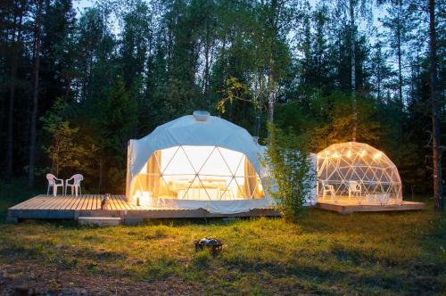 two domes in a field with a table and a chair at Bubble House glamping tent Odulemma in Odulemma