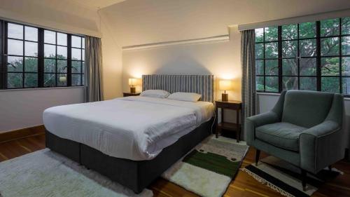 a bedroom with a bed and a chair and windows at Mountain view villa heated pool Nyeri - 2352 in Kuhora Twana