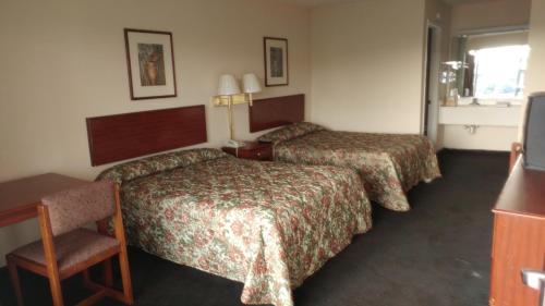 una habitación de hotel con 2 camas y una silla en Countryside Inn Motel, en Richmond