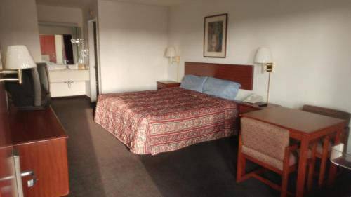 Habitación de hotel con cama, escritorio y TV. en Countryside Inn Motel, en Richmond