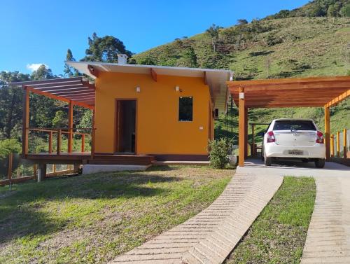 een huis met een auto ervoor geparkeerd bij Chalé Topázio Gonçalves in Gonçalves