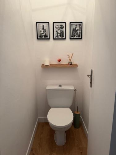 a bathroom with a toilet with three pictures on the wall at Les Trinitaires in Sarzeau
