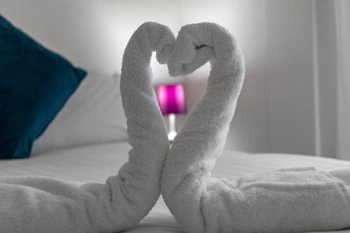 zwei Handtücher bilden ein Herz auf einem Bett in der Unterkunft City Pulse Apartment- Short Stays UK in Exeter