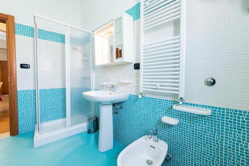 ein blau gefliestes Bad mit einem Waschbecken und einer Dusche in der Unterkunft CORAL BAY Apartment in Porto Cesareo