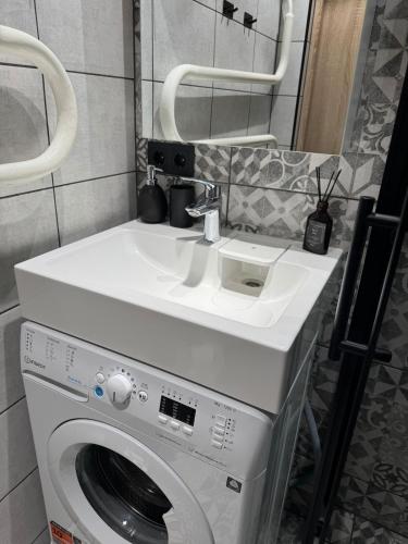 a bathroom with a sink and a washing machine at Cozy Center Apartment in Jelgava