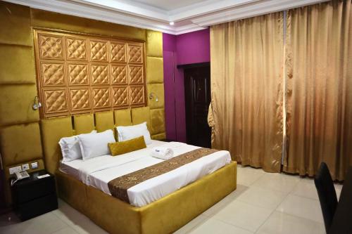 1 dormitorio con 1 cama grande con paredes moradas y amarillas en El-nido By Kdove Hotels and Lounge, en Omole