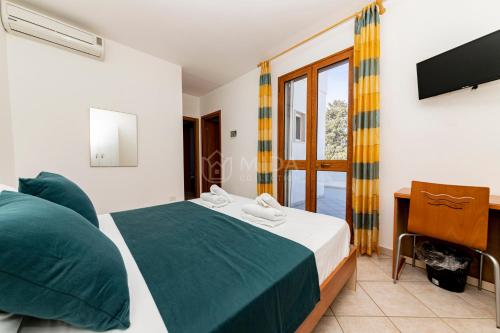 een slaapkamer met een bed, een bureau en een televisie bij Giorni Salentini in Torre Lapillo