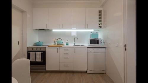 una cucina bianca con un lavello e un forno a microonde di Pópulo Mar a Ponta Delgada