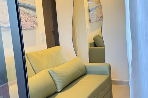 a yellow chair in a room with a mirror at Sofisticado 2Q 200m do Mar 1 min do Centrinho in Porto De Galinhas