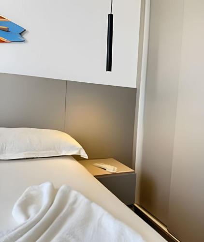 a bedroom with a bed with a white pillow and a cabinet at Sofisticado 2Q 200m do Mar 1 min do Centrinho in Porto De Galinhas