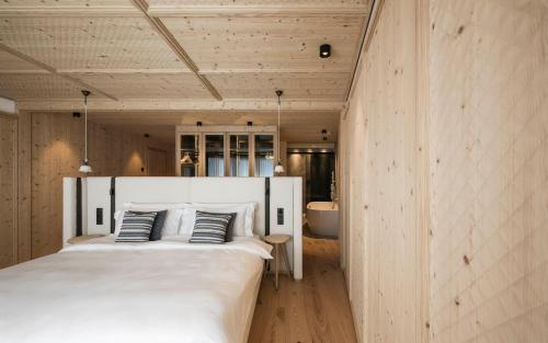 a bedroom with a large white bed and a bathroom at Muliné Lodge in Selva di Val Gardena