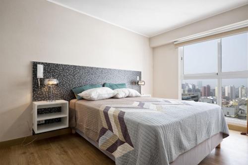 a bedroom with a large bed and a large window at Wasi Apartment Pardo in Lima