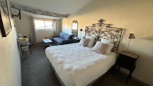 ein Schlafzimmer mit einem großen Bett und einer Couch in der Unterkunft Logis Hôtel la Vallée de l'Arc in Trets