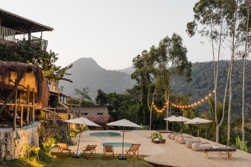 a resort with a pool and chairs and umbrellas at Mōmento Itamambuca in Ubatuba