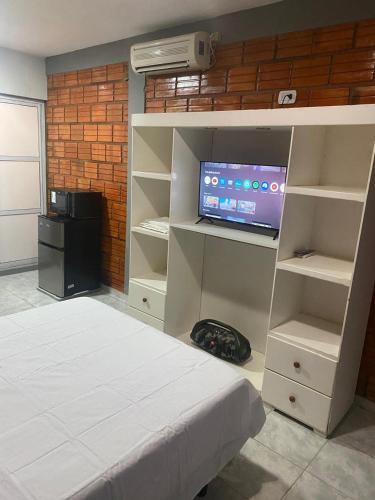 une chambre avec un lit, une télévision et des étagères dans l'établissement Libertad, à Clorinda