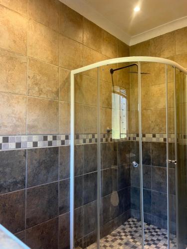 una doccia con una porta in vetro in un bagno di Protea Guesthouse a Phalaborwa