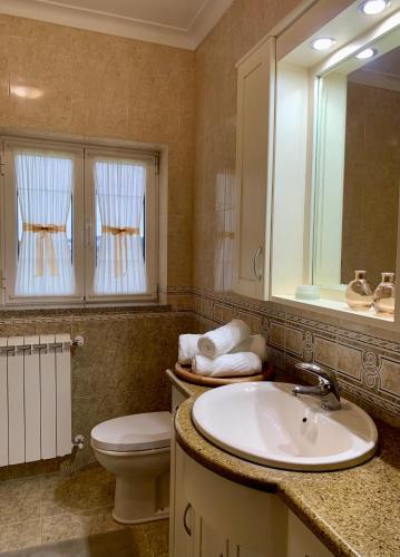 a bathroom with a sink and a toilet and a mirror at Casa Vista para a Serra in Casais do Livramento