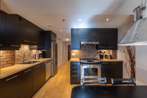 a kitchen with black cabinets and a stove at Les Immeubles Charlevoix - Le 1168 in Quebec City
