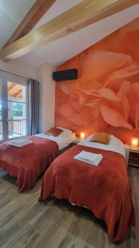 twee bedden in een kamer met een schilderij aan de muur bij LE COTTAGE DU PARC in Chambéon