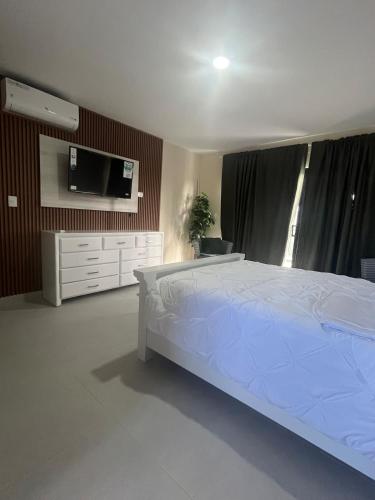 una camera da letto con un letto bianco e una tv di Villa Medrano 