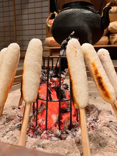 a grill with hot dogs and a pot on top at うご八かやぶ㐂 in Narazaki