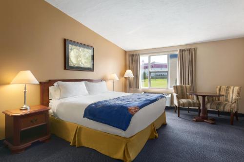 a hotel room with a bed and a window at Days Inn & Suites by Wyndham Moncton in Moncton