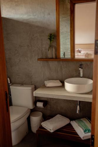 a bathroom with a sink and a toilet and a mirror at Casa Teçá in Guriú