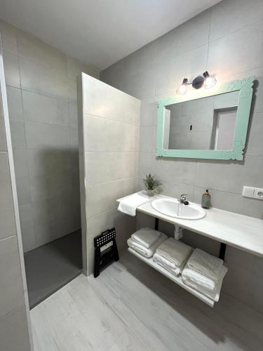 a bathroom with a sink and a mirror and towels at Señorón & Requesón in Olivenza