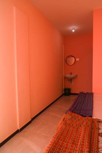 a room with orange walls and a rug in a room at Annu Mane Homestay in Gokarna