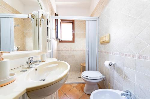 a white bathroom with a sink and a toilet at Maridea Flat in Porto Cesareo