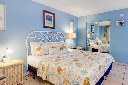 een blauwe slaapkamer met een bed en een spiegel bij Daytona Harbour Beach Resort 213 in Seabreeze