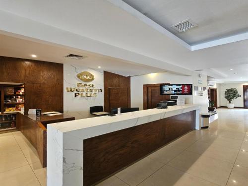 チワワにあるBest Western Plus Chihuahua Aeropuertoの受付とピザレストランがあるホテルのロビー