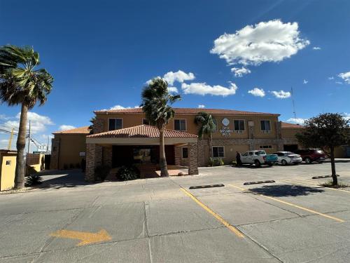 チワワにあるBest Western Plus Chihuahua Aeropuertoのヤシの木が茂るホテル前の駐車場