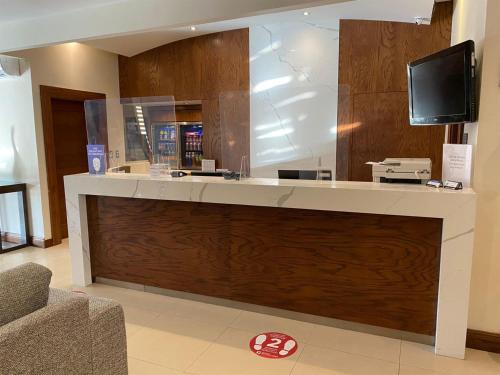 a lobby with a large counter with a tv on it at Best Western Plus Chihuahua Aeropuerto in Chihuahua