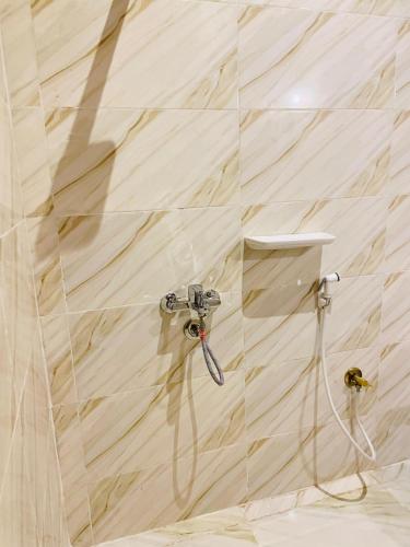 a shower with a hose attached to a wall at Shasha Siwa Retreat & Thermal Spring in Siwa