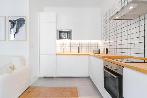 a white kitchen with white cabinets and a sink at Charming Lisbon 2BR Apartment with Balcony in Lisbon