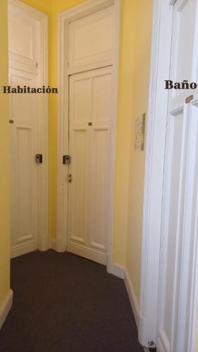 a hallway with two white doors and yellow walls at Hotel Frossard in Buenos Aires