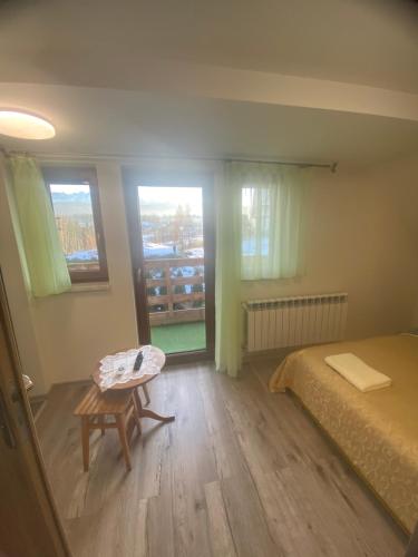 een slaapkamer met een bed, een tafel en ramen bij Kapacówka in Zakopane