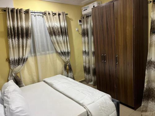 a bedroom with a bed and a wooden cabinet at E&V APARTMENT Berger Express in Iseri-Oke